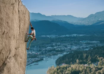 Promotional image of a rock climber high above a snowy valley for the 2024 Vancouver International Mountain Film Festival
